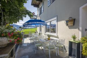 a patio with a table and chairs and an umbrella at Gasthof Aschenwald in Westendorf