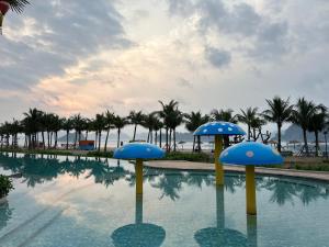uma piscina com guarda-sóis azuis na água em Rosa Villa - Sonasea - Vân Đồn 