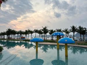 a swimming pool with blue umbrellas in the water at Rosa Villa - Sonasea - Vân Đồn in Thâm Câu