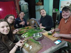 grupa ludzi siedzących przy stole przygotowujących jedzenie w obiekcie Sunrise Farmstay w Katmandu