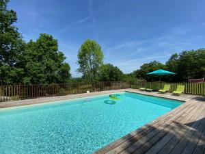 einen Pool mit einer Terrasse und einem Sonnenschirm in der Unterkunft Gîte les chênes verts - Périgord noir in Saint-Amand-de-Coly