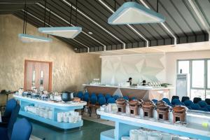 a room with blue chairs and a counter with a person at Azana Style Hotel Tulungagung in Tulungagung