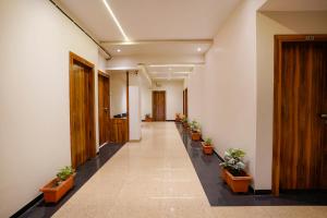 un couloir d'un immeuble de bureaux avec des plantes en pot dans l'établissement FabHotel Priya Lodging, near Ojhar Airport, à Nashik