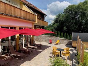 patio z krzesłami, stołami i czerwonymi parasolami w obiekcie Ferienpark Schwarzholz F**** w mieście Viechtach