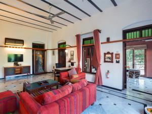 a living room with red couches and a tv at The House of MG-A Heritage Hotel, Ahmedabad in Ahmedabad