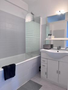 ein weißes Bad mit einem Waschbecken und einer Dusche in der Unterkunft Appartement vue Parc Montjuzet avec garage in Clermont-Ferrand