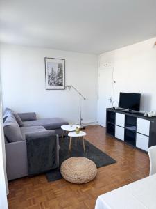 ein Wohnzimmer mit einem Sofa und einem Tisch in der Unterkunft Appartement vue Parc Montjuzet avec garage in Clermont-Ferrand