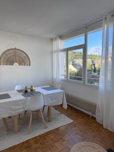 ein Esszimmer mit einem Tisch und einem großen Fenster in der Unterkunft Appartement vue Parc Montjuzet avec garage in Clermont-Ferrand