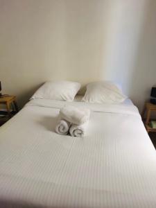 a white bed with two rolls of towels on it at A 10 min de La Défense et à 20 min de Paris in Suresnes