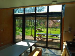 a room with a large window with a picnic table outside at Le Baugyte - Gite de GROUPE - 14 lits simples in Marcigny