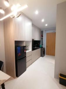 a large kitchen with a black refrigerator and cabinets at Simple Nice Stay @ Riverine Diamond Petanak in Kuching