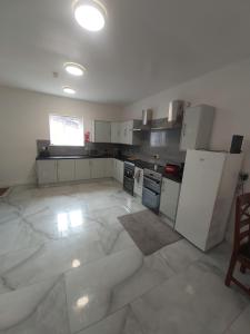 a large kitchen with white appliances and a large tile floor at Masfol home from home in Oldham