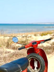 - un scooter rouge garé sur la plage dans l'établissement Nella spiaggia più bella, à Santa Maria Del Focallo