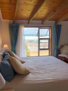 a bedroom with a bed with a view of the beach at Pumlani Kei Mouth in Kei-mouth Village