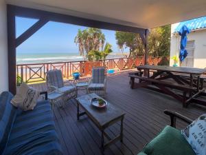 a deck with a picnic table and chairs and the beach at Pumlani Kei Mouth in Kei-mouth Village