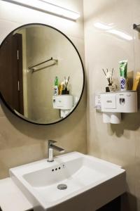 een badkamer met een witte wastafel en een spiegel bij SISO homestay - Enchanting Studio in Hanoi