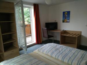 a bedroom with a bed and a desk and a window at Pension Schneider, Bad Gögging in Neustadt an der Donau
