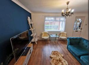 een woonkamer met een tv en een blauwe muur bij Eltam Cresent in Thornaby on Tees