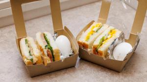 tres sándwiches y huevos en cajas en un mostrador en Tabist MEN‘TEL Kitami, en Kitami