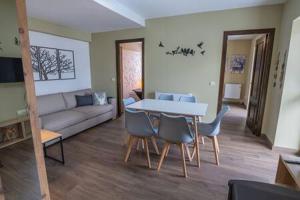 Una sala de estar con una mesa y sillas y un sofá. en Apartament el Cabirol, en La Molina