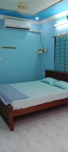 un letto in una camera con parete blu di Centaurus Homestay near Trichy Airport a Tiruchchirāppalli