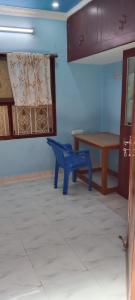 a blue room with a table and a blue chair at Centaurus Homestay near Trichy Airport in Tiruchchirāppalli