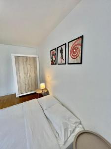 a bedroom with a white bed and three pictures on the wall at Sweet Escape Paris Centre - 3 bds- terrasse - Stade de France - Montmartre in Saint-Ouen +17 photos