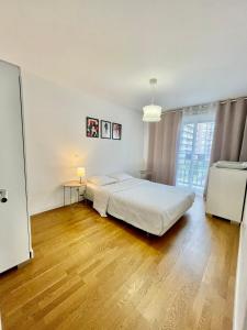 een witte slaapkamer met een bed en een houten vloer bij Sweet Escape Paris Centre - 3 bds- terrasse - Stade de France - Montmartre in Saint-Ouen