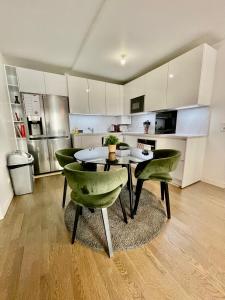 a kitchen with a table and some green chairs at Sweet Escape Paris Centre - 3 bds- terrasse - Stade de France - Montmartre in Saint-Ouen