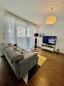 een woonkamer met een bank en een flatscreen-tv bij Sweet Escape Paris Centre - 3 bds- terrasse - Stade de France - Montmartre in Saint-Ouen