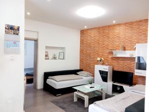 uma sala de estar com um sofá preto e uma parede de tijolos em Apartment Centar em Slavonski Brod