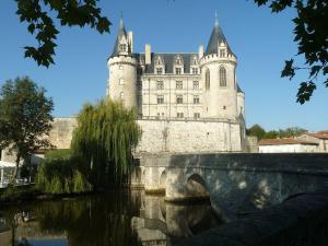 a castle with a bridge in front of a building at Maison Chinsa in Saint-Angeau