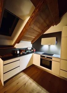 a kitchen with white cabinets and a black oven at Hotel Des Alpes in Inden