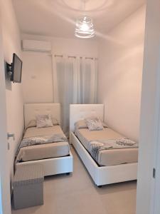 twee bedden in een kamer met witte muren bij Costamia Casa Vacanze in Santa Maria di Castellabate