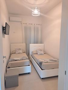2 łóżka w pokoju z białymi ścianami w obiekcie Costamia Casa Vacanze w mieście Santa Maria di Castellabate
