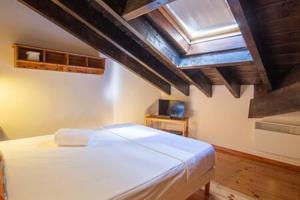 Un dormitorio con una cama blanca en una habitación con techos de madera. en Duplex la Solana, en Err 11 fotos más