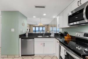 a kitchen with white cabinets and a black counter top at Commodore 504 in Panama City Beach
