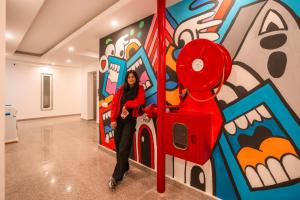 a woman is standing in front of a mural at goSTOPS Gurugram in Gurgaon