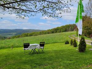 a table and two chairs in a field with a flag at Ferienwohnung Landidylle in Birx