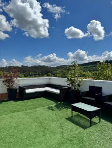 un patio con sofá, mesa y césped en jardines del pas en Oruña