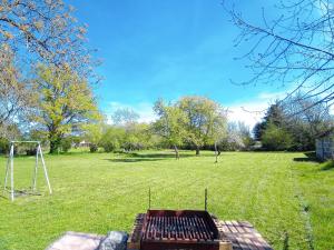 a barbecue grill in a field with a swing at Le Petit Aigu in Clugnat