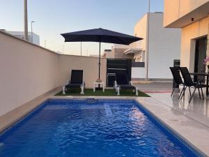 a swimming pool with two chairs and an umbrella at Villa avec piscine in Daya Vieja