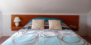 a bed with a blue blanket and two pillows at Le Petit Aigu in Clugnat