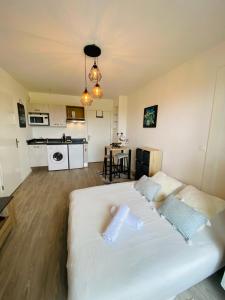 een groot wit bed in een kamer met een keuken bij L'Escale Cosy - Disneyland Paris in Serris