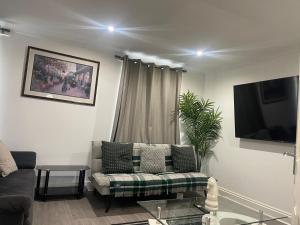 a living room with a couch and a tv at Majestic 2 bedroom House Milton Keynes in Milton Keynes