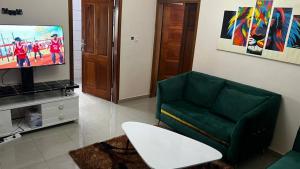- un salon avec un canapé vert et une télévision dans l'établissement Magistral apparts, à Yaoundé