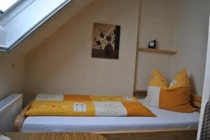 Bett mit orangefarbenen Kissen in einem Zimmer in der Unterkunft Ferienwohnung Karin in Marienhafe