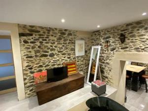 a living room with a tv and a stone wall at LA CAVE in Bouleternère