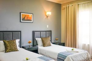 Una habitación de hotel con dos camas y una ventana. en Atlantic Pearl Guest House Rivonia, en Johannesburgo