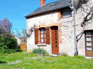 an old brick house with a wooden door and windows at Le Petit Aigu in Clugnat